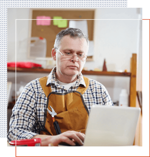 A man in an apron using a laptop.